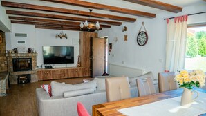 A living room with a fireplace, television, sofa, and dining table. - Avrigelli, kids&family friendly (Avrig)