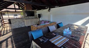 An outdoor patio with a wooden table, chairs, and a cushioned seating area. - Avrigelli, kids&family friendly (Avrig)