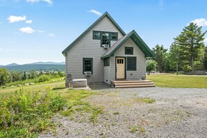 Une maison à deux étages, dotée d’un toit végétalisé et d’une allée gravillonnée.