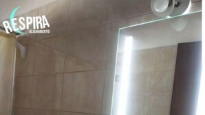 Une salle de bain équipée de toilettes, d’un lavabo et d’un miroir avec un éclairage au-dessus.