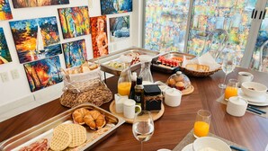 Ein Frühstücksbuffet mit verschiedenen Speisen, Getränken und Blick auf farbenfrohe Wandbilder.