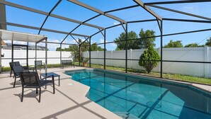 Une piscine extérieure couverte avec un espace patio comprenant des chaises et une table.