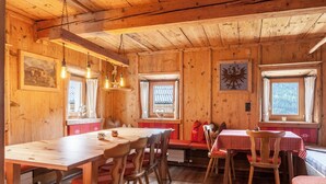 A wooden interior with a dining table, chairs, benches, and windows. - Neuhaus Alm Holiday Home with Mountain Views, Open Terrace and Wi-Fi (Gerlosberg)