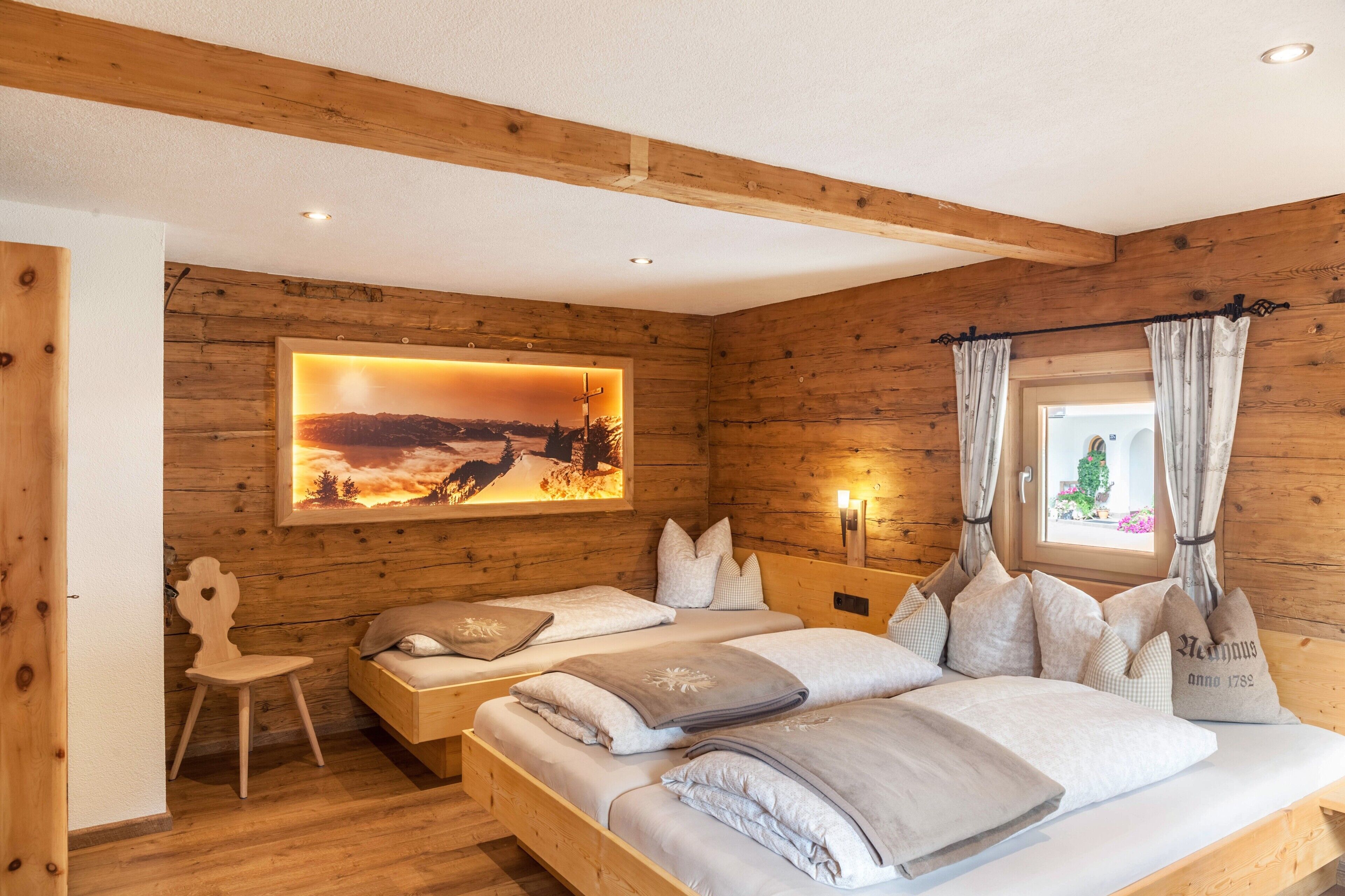 Una habitación de cabaña de madera con dos camas, un cuadro y una ventana con cortinas.