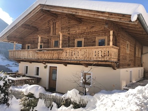 A wooden chalet with a balcony, a door, and a window. - Neuhaus Alm Holiday Home with Mountain Views, Open Terrace and Wi-Fi (Gerlosberg)