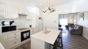 Una cucina moderna con mobili bianchi, un'isola centrale e un'area pranzo con divano e sedie.