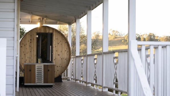 Uma cabana de madeira com varanda, chaminé e vista para a paisagem.
