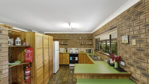 Une cuisine compacte avec des meubles de rangement en bois, un four encastré et un plan de travail vert.