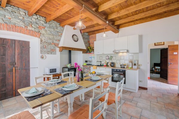 A kitchen with white cabinets, a stone wall, and a wooden ceiling.