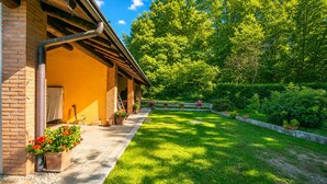 A brick building with a covered porch, a well-maintained lawn, and a garden with potted plants. - Timeless l'Antico Mulino Della Bozza in Brebbia, Brebbia, Italy (Brebbia)