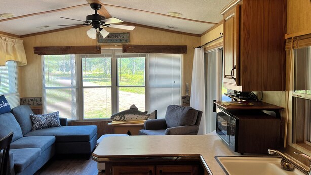 A cozy RV interior with a kitchenette, a dining area, and a seating space with a view of the outdoors. - The Bears Den cabin w screened porch in campground on bike trail. (Boulder Junction)