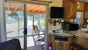 A compact RV kitchen with wooden cabinets, a microwave, a small TV, and a fire extinguisher. - The Bears Den cabin w screened porch in campground on bike trail. (Boulder Junction)