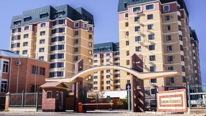 A multi-story residential building with a curved entrance archway, multiple balconies, and a sign indicating "EUROPA RESIDENCE". - Europa Residence (Atyrau)
