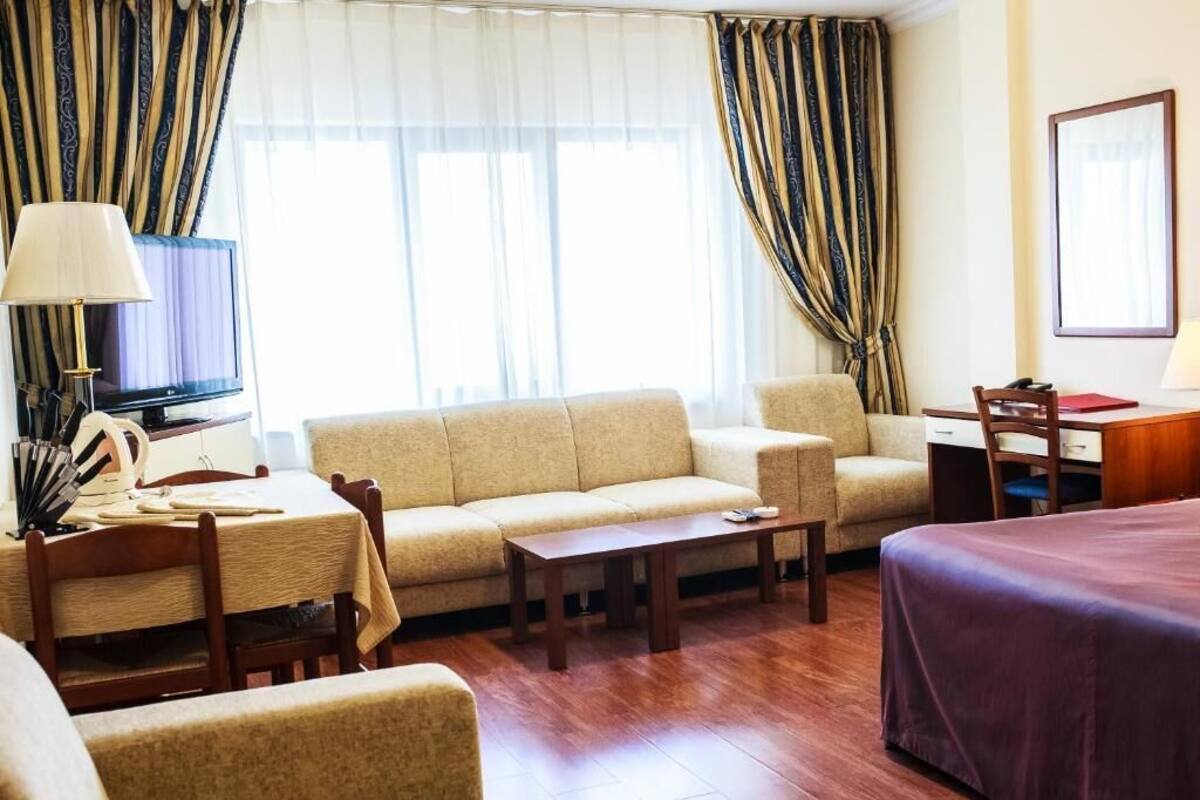 Una habitación de hotel con sofá, cama, escritorio y televisión.