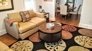 Una sala de estar con un sofá color crema, una mesa de centro y un comedor con mesa y sillas.