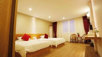 A hotel room with two beds, a desk, a chair, and a window with curtains.