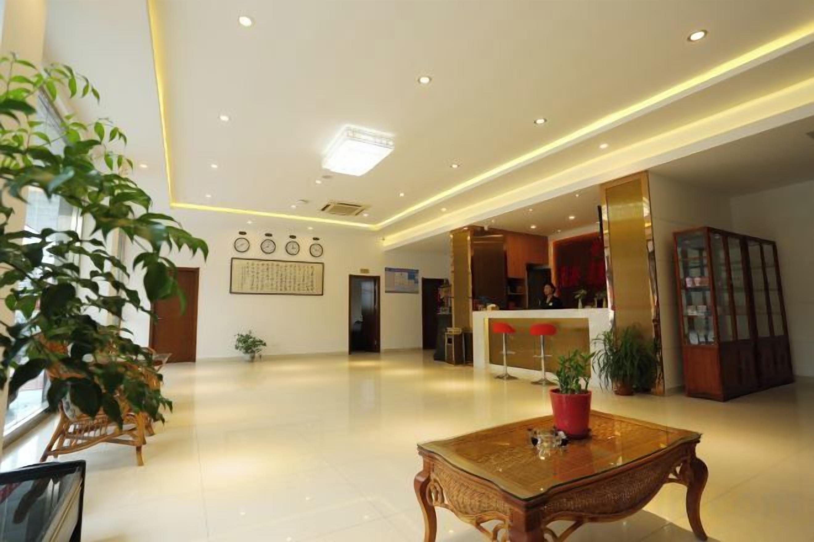 A hotel lobby with a reception desk, a reception area, and a seating area with a table and chairs.