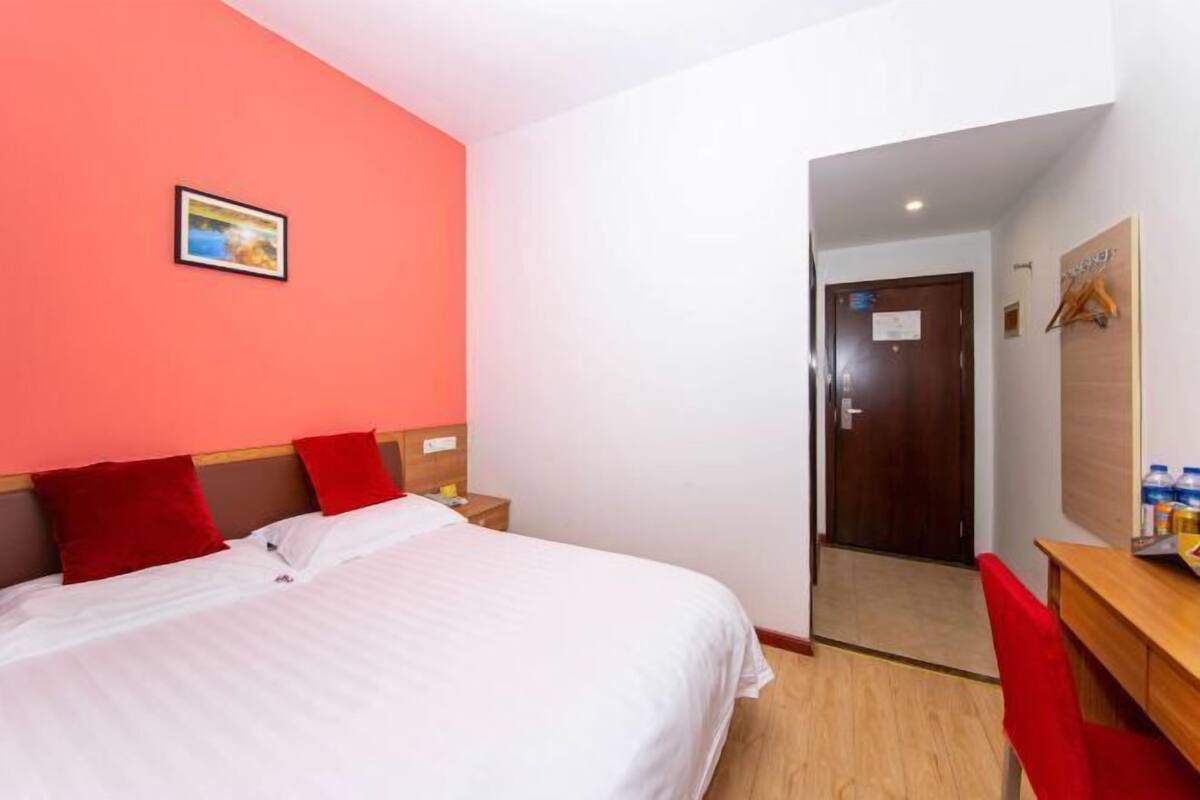 A hotel room with a bed, a desk, and a door leading to another room.