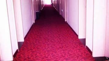 A long, narrow hallway with a red carpet and white walls.