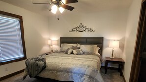 A bedroom with a bed, two bedside tables, a ceiling fan, and a decorative wall piece. - Perfect for a TEAM of people! (Hastings)