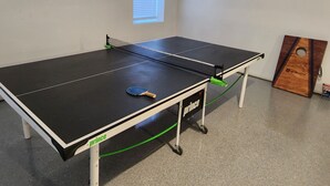 A ping pong table with a paddle, a green cord, and a wooden board with "No Sports" written on it. - Perfect for a TEAM of people! (Hastings)