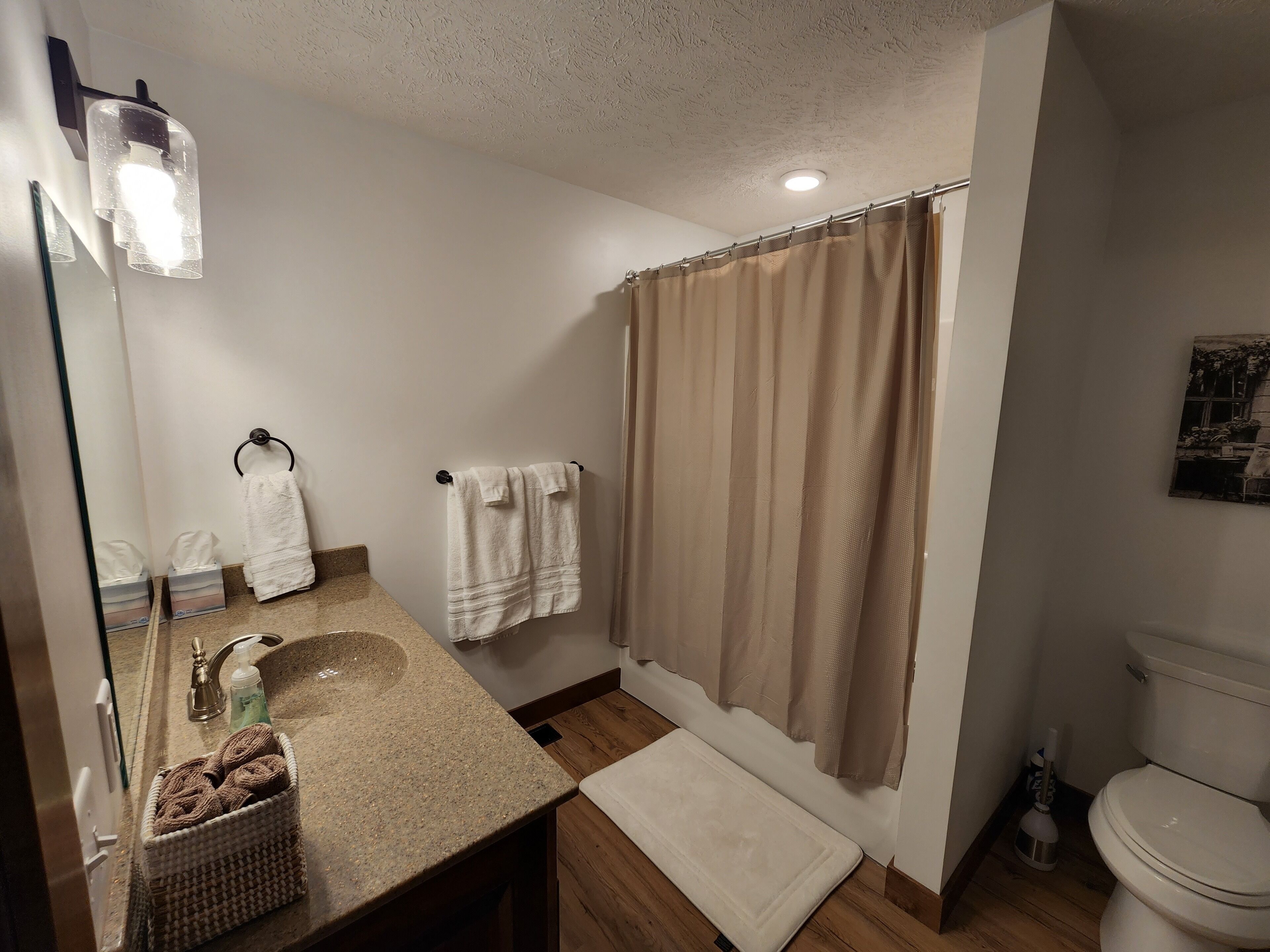 Een badkamer met een wastafel, spiegel, handdoekhouder, douchegordijn en toilet.
