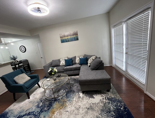 A living room with a grey sectional sofa, a blue armchair, a coffee table, and a patterned rug.