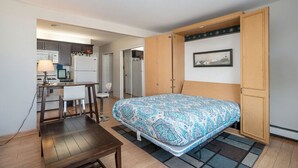 A compact room with a bed, a desk, and a kitchenette. - Beautiful Pool and Lake View (South Haven)