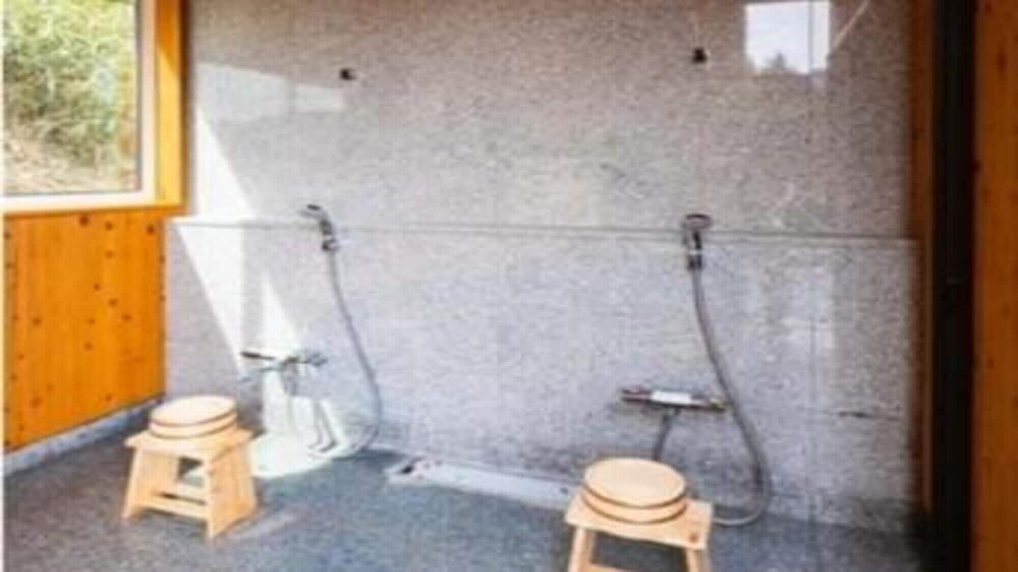 A bathroom with two wooden stools, a granite wall, and a shower area.