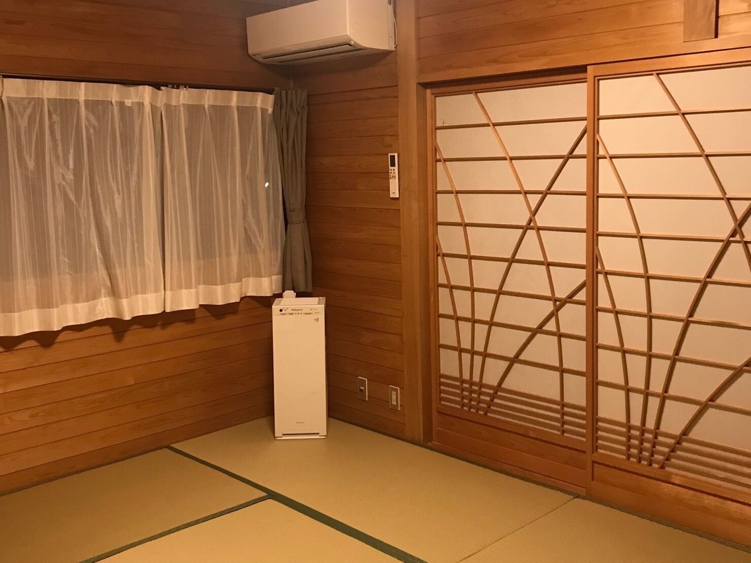 A traditional Japanese room with tatami flooring, a shoji screen door, and a white air conditioning unit.
