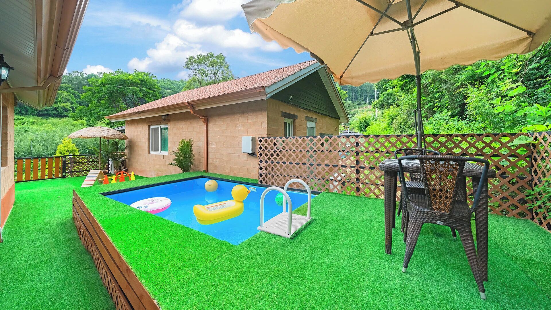 A backyard with a swimming pool, artificial grass, a house, and a patio chair.