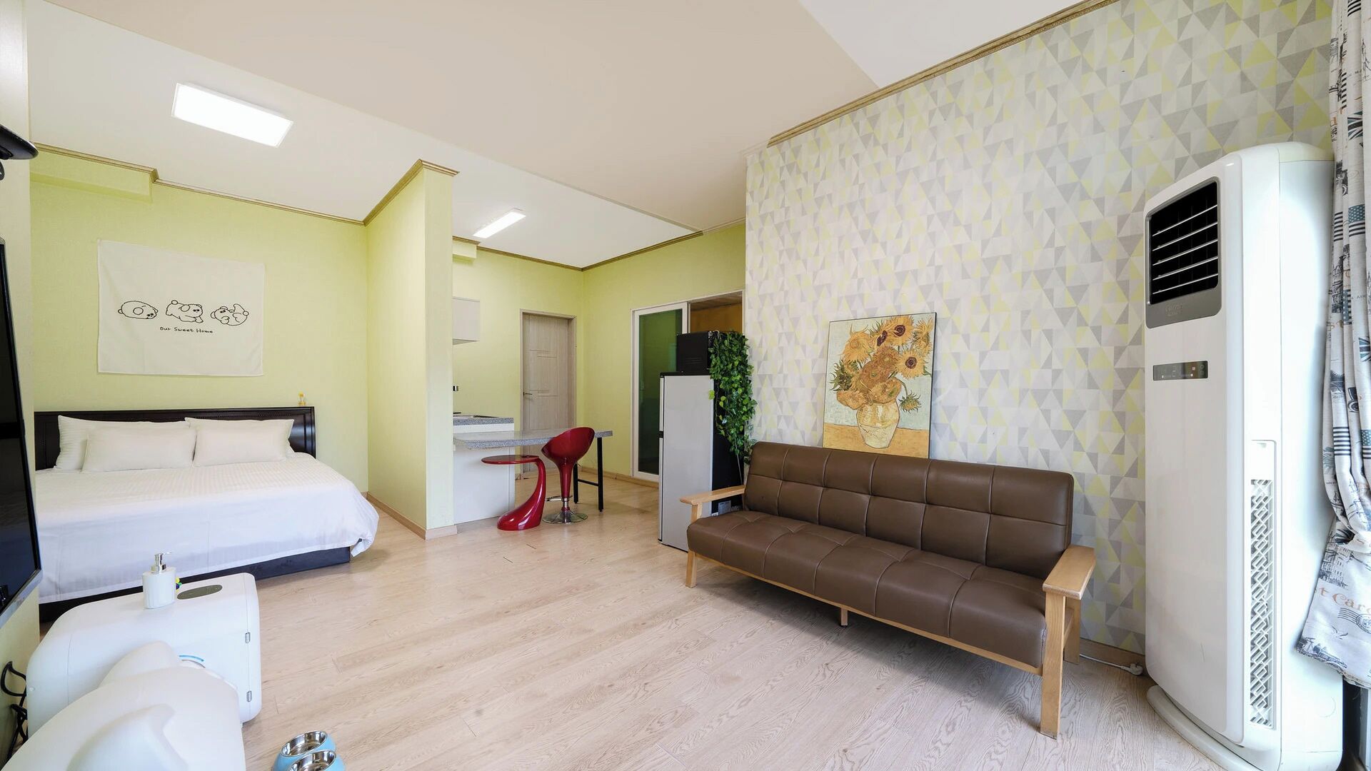 A hotel room with a bed, a sofa, a small dining area, and a kitchenette.