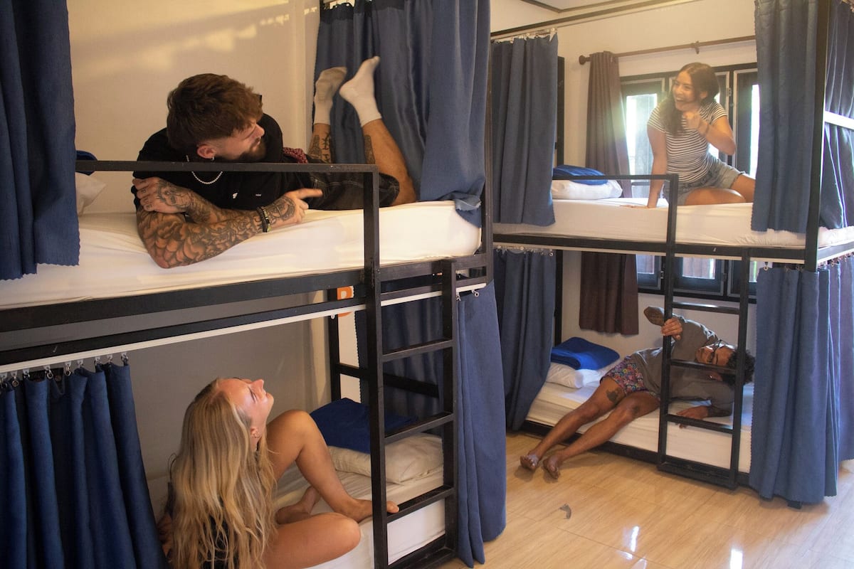 Une chambre avec un lit superposé, des rideaux, une fenêtre et un miroir.