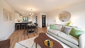 Un salon moderne avec un canapé gris, une table basse et un coin repas comprenant une table et des chaises.