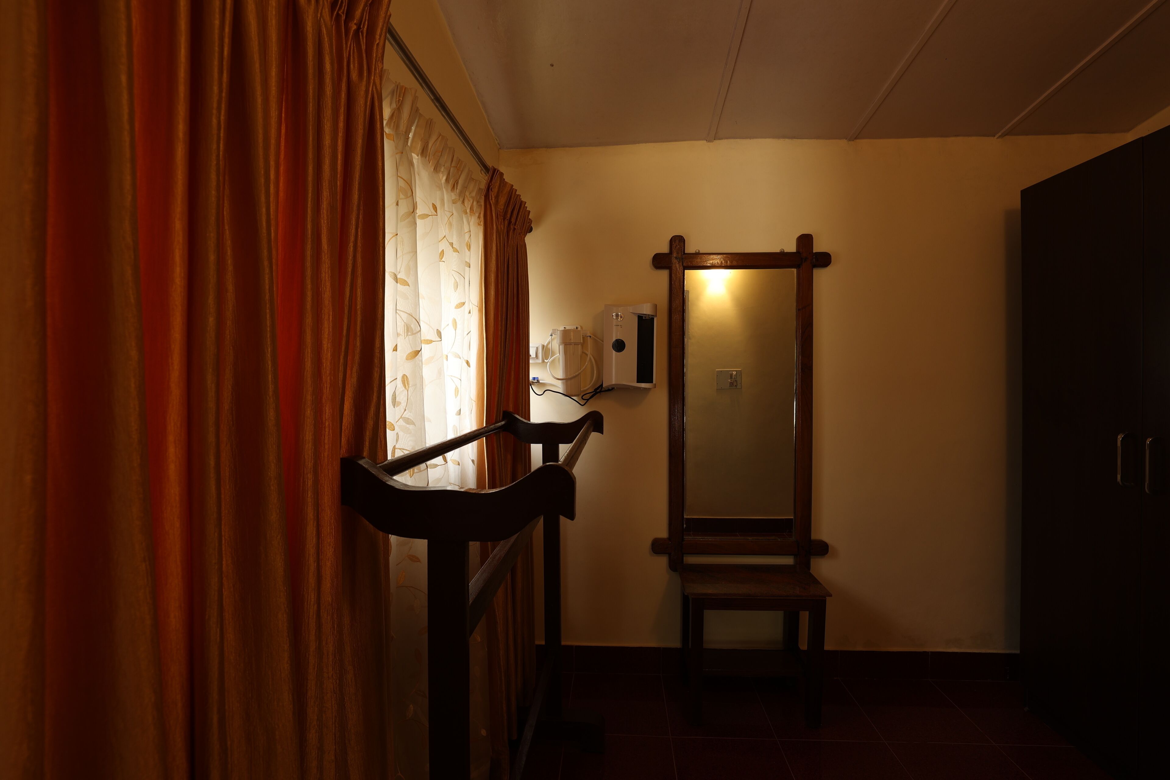 A room with a wooden bench, a mirror, and a window with curtains.