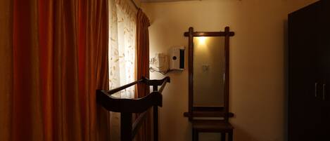 A room with a wooden bench, a mirror, and a window with curtains.