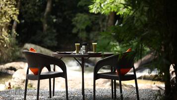 Une table installée à l’extérieur, avec des chaises, une machine à café et des tasses.