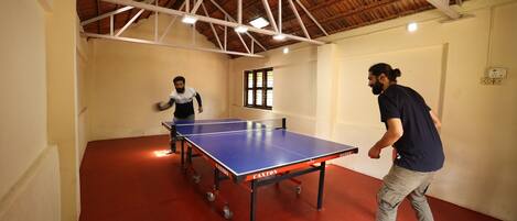 A ping pong table in a room with a high ceiling and wooden beams.
