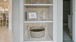 A white shelving unit with decorative items including a starfish, a wicker basket, and a framed picture.