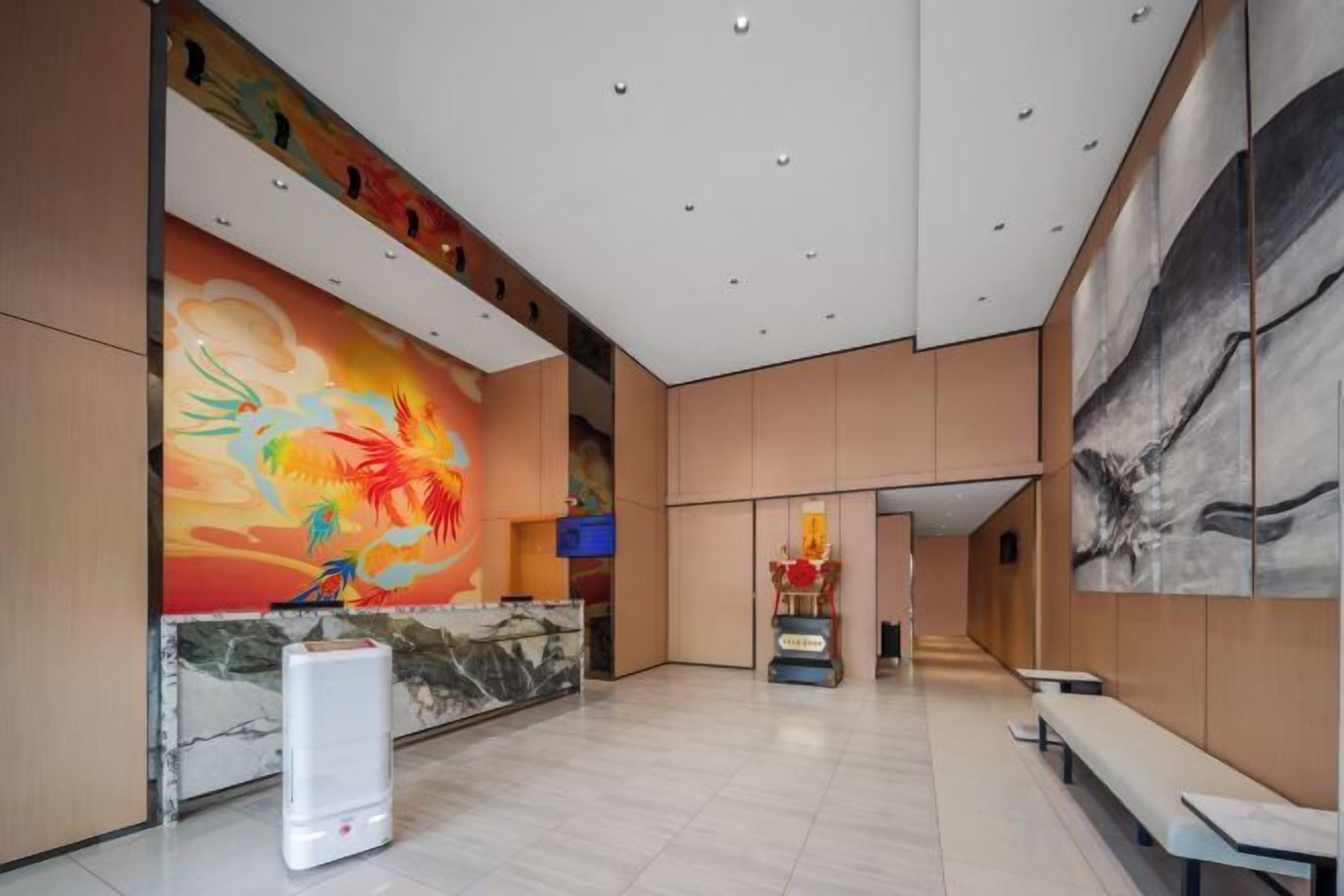 A spacious lobby with a reception desk, seating area, and artwork on the walls.