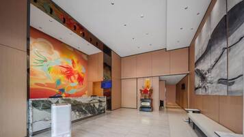 A spacious lobby with a reception desk, seating area, and artwork on the walls.