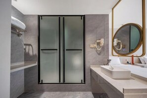 A modern bathroom with a glass shower enclosure, a white sink, and a large mirror with a gold frame. - dinghaophotel (Taizhou)