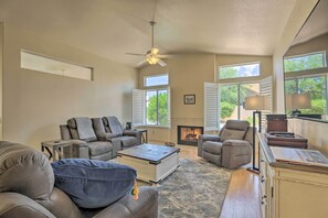 A spacious living room with a fireplace, leather sofas, a coffee table, and large windows.