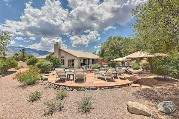 A patio area with outdoor seating and a pool, surrounded by landscaping and a mountain view.