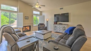 A living room with a fireplace, leather sofas, a coffee table, and a TV. - Saddlebrooke Home w/ Private Pool & Amenities (Tucson)