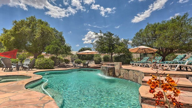 A clear blue pool with a waterfall feature, surrounded by lounge chairs and umbrellas. - Saddlebrooke Home w/ Private Pool & Amenities (Tucson)