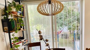 A round wooden dining table with four chairs, a green glass vase with dried flowers, and a woven pendant light. - 3 Br by park hayarkon 1min  2 Ichilov (Tel Aviv)