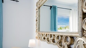Un baño con tocador blanco, espejo con marco decorativo, toalla y lámpara.