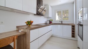 Una cocina moderna con armarios blancos, encimera de madera y un tazón de fruta.