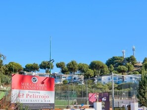 Un court de tennis avec une enseigne indiquant le club de tennis de Miraflores et le restaurant El Pelitrojo.